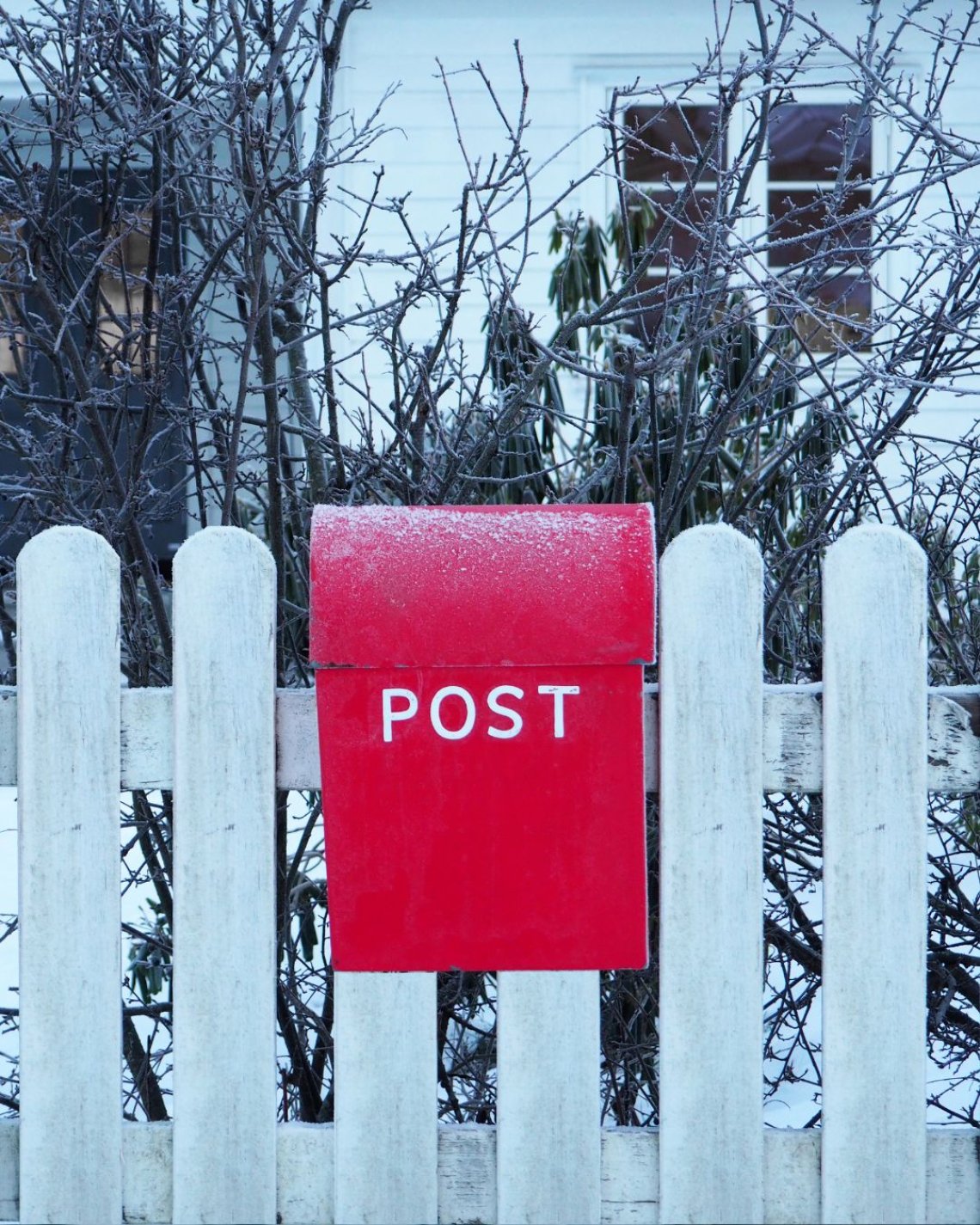 Rød postkasse på hvitt gjerde